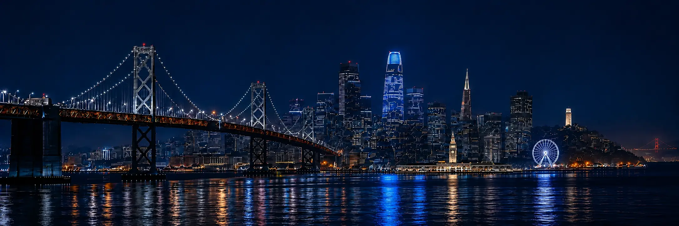 San Francisco night skyline with the Ferry Building, waterfront Ferris wheel and illuminated bridges